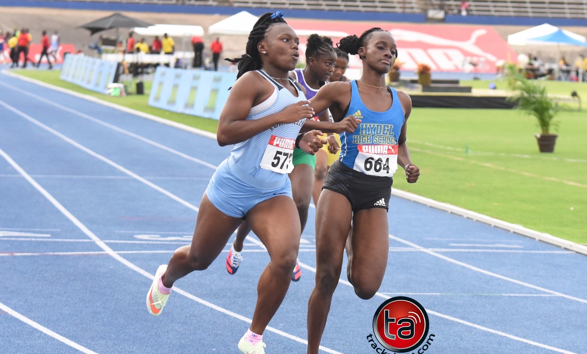 Female sprinters racing on blue track